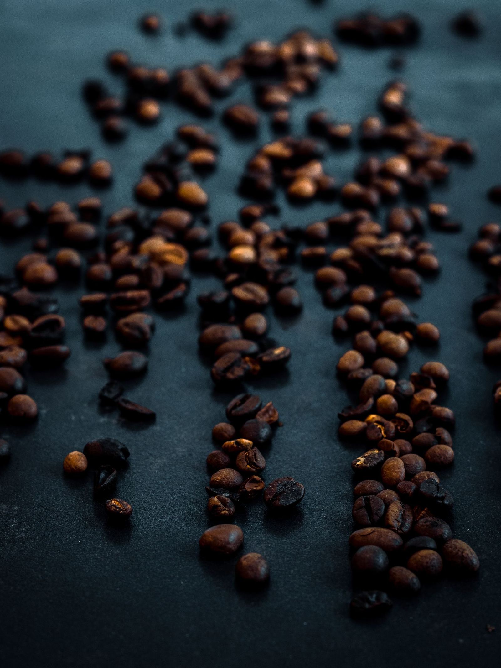 Coffee beans scattered across a dark surface.