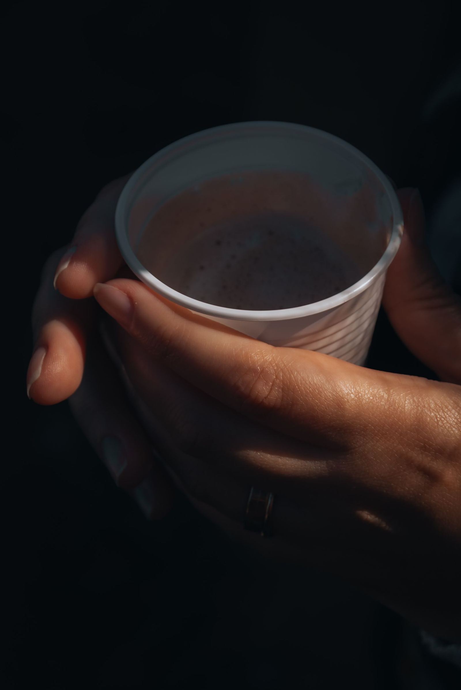 A hand around a cup in near darkness.