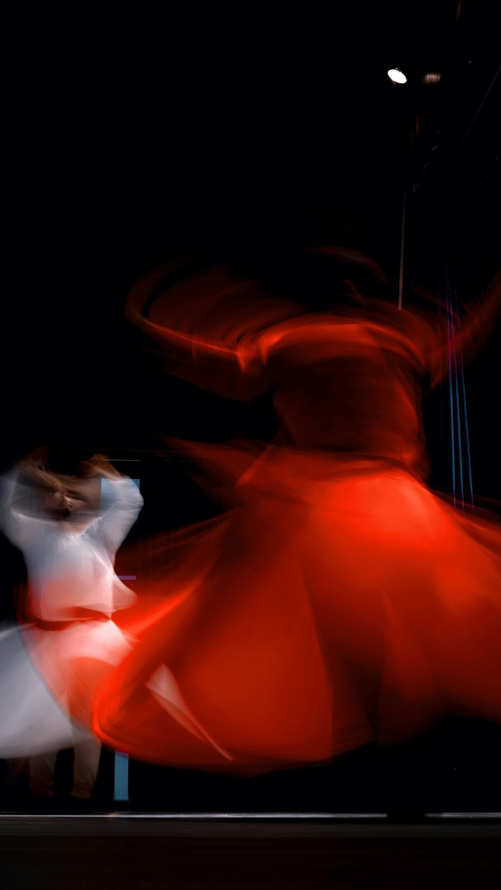 A person spinning in a vibrant red skirt, captured as motion blur.