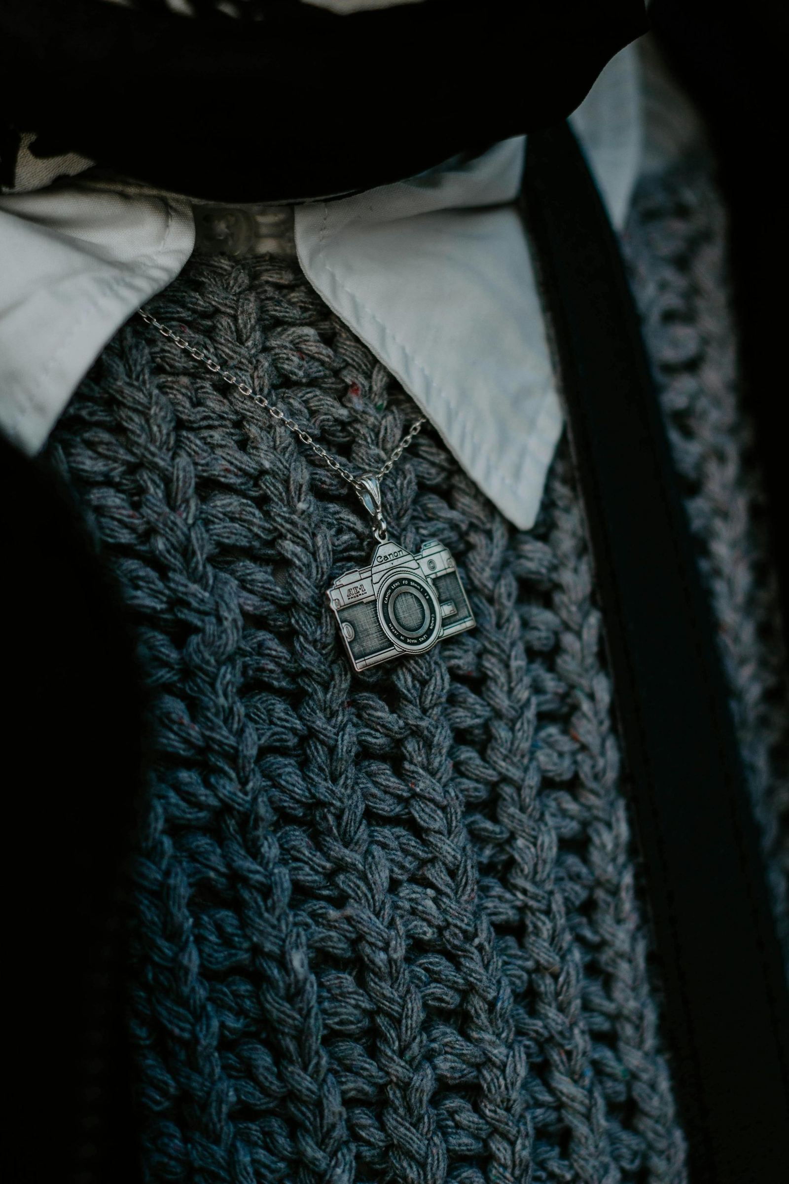 Close-up of a person's neck and chest wearing a camera pendant.