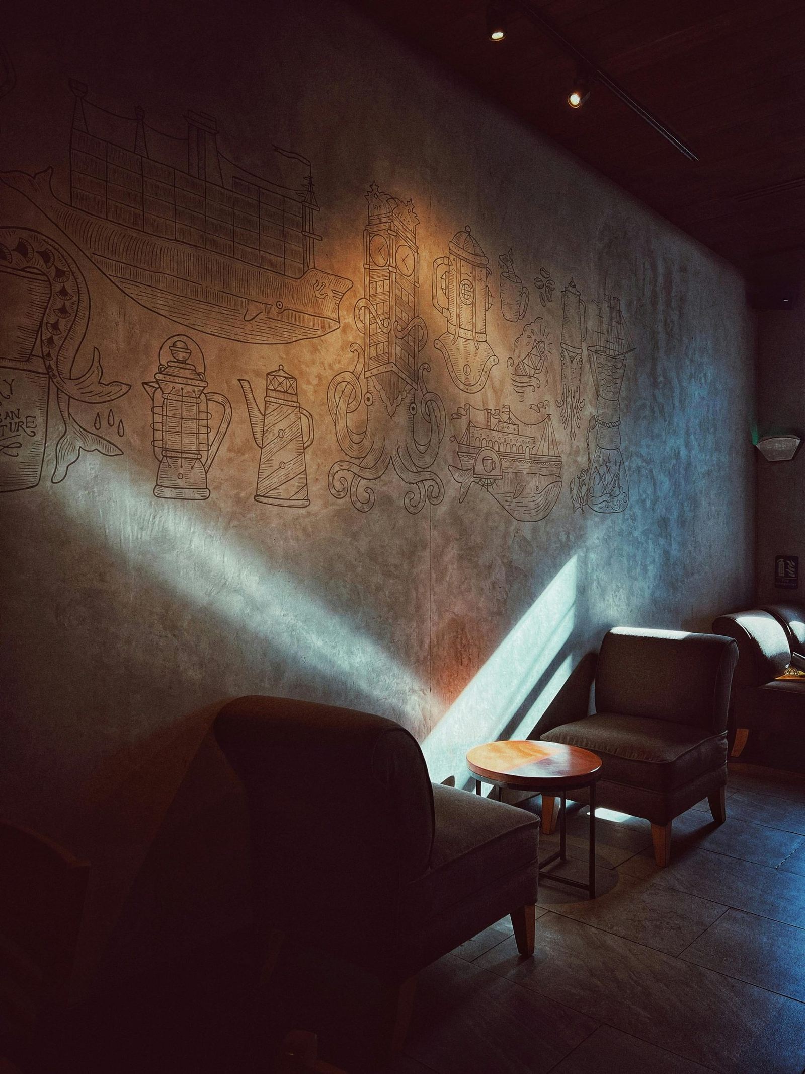 A cozy corner in a dimly lit cafe with a shaft of light across the room.