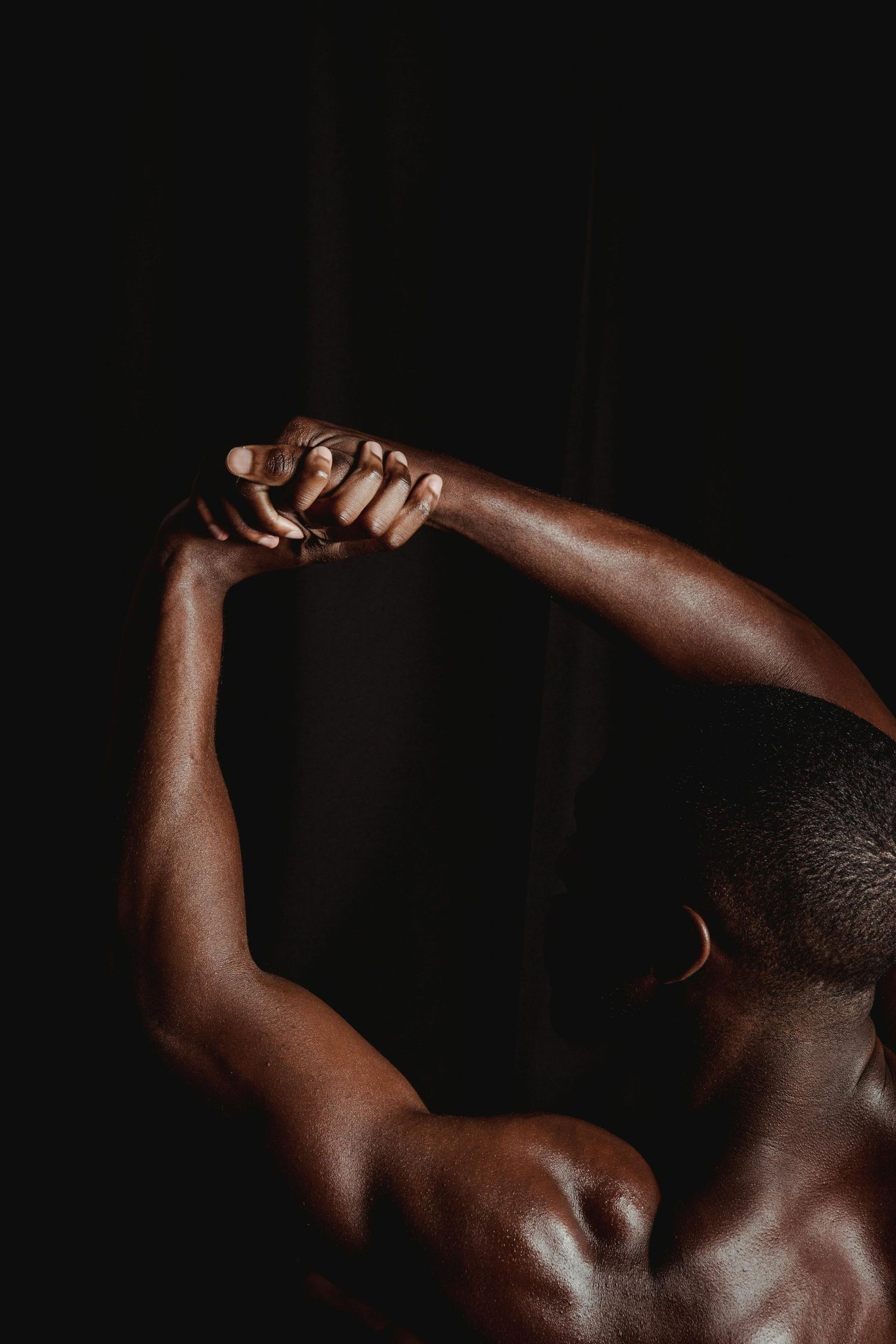 Close-up of two arms raised and clasped overhead in movement.