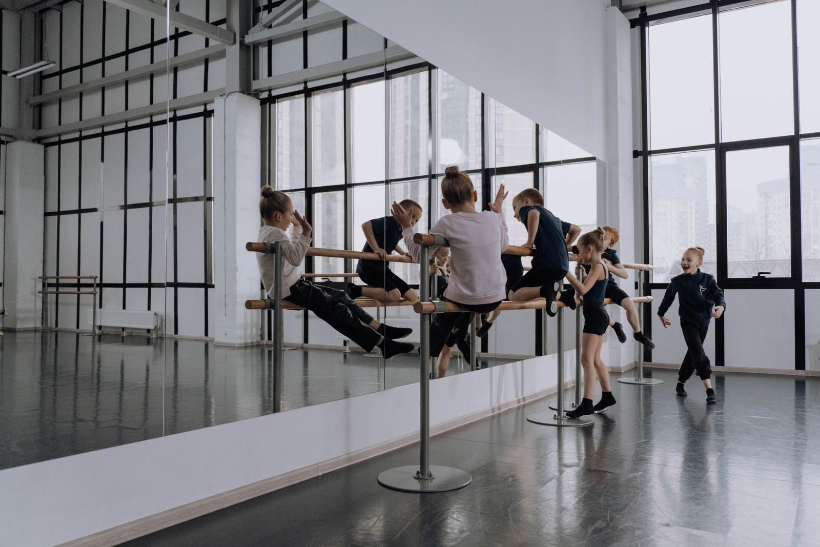 The studio floor with barre, mirrored wall and tall windows.