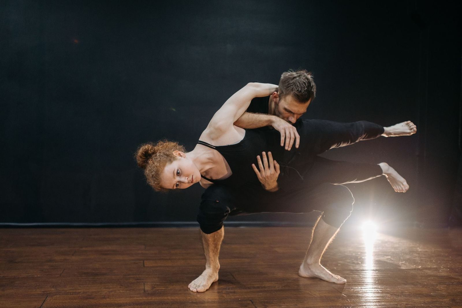 Two dancers lifting, lit from behind.